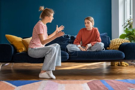 Photo for Annoyed woman mom talking arguing with teen girl daughter sitting on couch at home. Psychological puberty and relationships family problem, mutual misunderstanding, motherhood, parenthood concept. - Royalty Free Image
