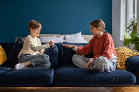 Photo for Two kids boy and girl friends play rock paper scissors hand game while sitting on sofa at home. Caucasian children brother and sister playing together. Indoor entertaining activities for siblings - Royalty Free Image