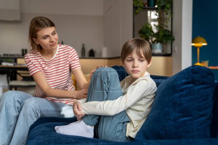 Photo for Loving mother trying to speak with upset depressed teen son while sitting together on sofa at home, mom comforting teenage boy child, showing support. Anger in adolescents. Kid problem concept. - Royalty Free Image