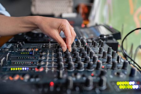 Photo for Woman radio DJ plays music at radio station studio on mixing console, hand close-up. Disc jockey working on tv, recording sound, audio podcast, creating music in modern professional sound studio. - Royalty Free Image