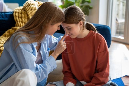 Photo for Caring foster mother connects with teenage daughter while sitting on floor at home. Smiling mother and schoolgirl chatting relaxed gossip about school share secrets. Close happy family relationships. - Royalty Free Image