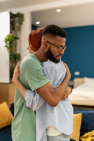 Photo for Young multiracial couple man and woman hugging while making up at home, loving supportive husband embracing wife gently, showing love and support. Understanding in relationships, - Royalty Free Image