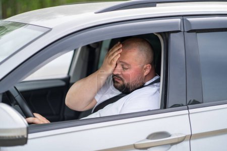 Photo for Tired overweight man drives car with broken air conditioner in hot summer weather. Male wiping sweat from face suffering from heat, stuffiness standing in road traffic. Exhausted overheated man. - Royalty Free Image