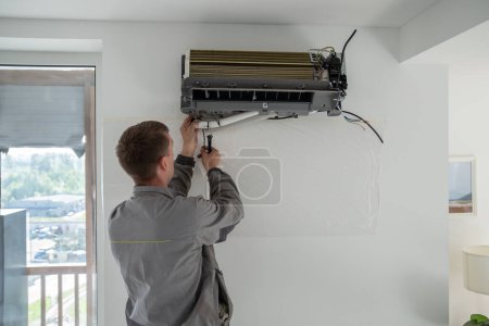 Photo for Installation of air conditioner by professional specialised climate control service in apartment. Repair and maintenance of air conditioned equipment. Cleaning of filters in ventilated systems. - Royalty Free Image