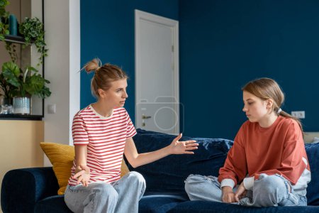 Photo for Misunderstanding mother and teenage girl. Excited mom spread arms while talk to bored teen daughter. Serious conversation between parents and child about problems of adolescence of transition age - Royalty Free Image