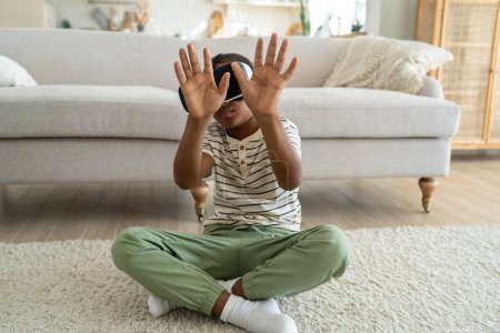 Téléchargez les photos : Enfants numériques. Gros plan d'un petit garçon afro-américain curieux portant des lunettes VR passant du temps en métaverse pendant son temps libre. Réalité augmentée pour les enfants, réalité virtuelle et éducation à domicile - en image libre de droit