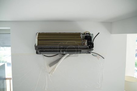 Foto de Instalación sistema de aire acondicionado en la pared blanca en el apartamento, primer plano de la oficina. Tecnología inversor sistema de aire acondicionado en apartamento. Reemplazo de ventilación en casa. Control de la temperatura - Imagen libre de derechos