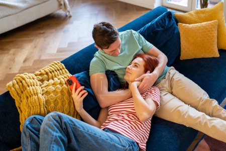 Photo for Caring man gentle hug wife enjoying leisure time together, resting on sofa. Smiling woman lying on loving husband laps at home. Romantic relationship. Happy couple relaxing on cozy couch at weekend. - Royalty Free Image