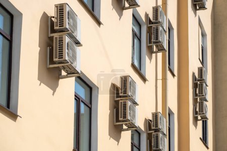 Photo for Facade of building with many air conditioners on windows in southern hot country. Yellow house exterior on city street. Escape from heat, creating favorable microclimate in urban apartments concept. - Royalty Free Image