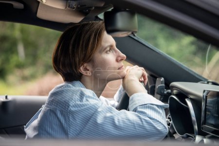 Téléchargez les photos : Femme frustrée d'âge moyen conduisant une voiture ayant des problèmes sur la route en attente dans un embouteillage avec la tête au volant. Conductrice nerveuse fatiguée ressent de la fatigue, la tristesse se tient sur la route à l'heure de pointe. - en image libre de droit