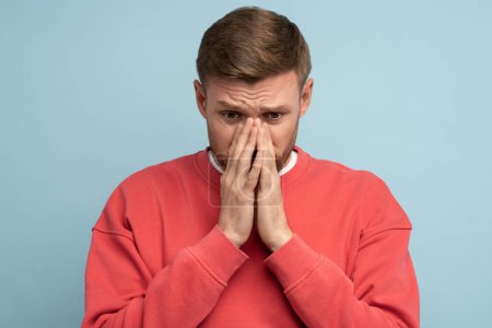 Photo for Frustrated depressed middle aged man closing face with hands isolated on studio blue background. Worrying about life troubles. Male feels disappointment having problems. Bearded guy has midlife crisis - Royalty Free Image