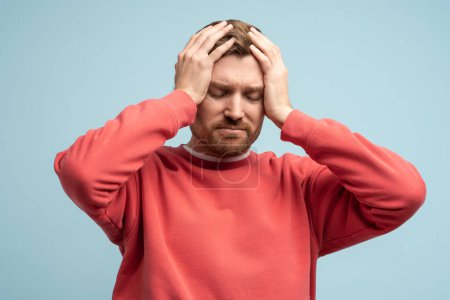 Photo for Portrait of sad man having life troubles holding head with suffering face on studio blue background. Frustrated, confused male with headache, life problems, midlife crisis. Stress, panic, desperation. - Royalty Free Image