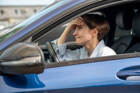 Photo for Burnout. Tired unhappy woman sitting inside car. Exhausted female of middle age running away from abusing husband make decision where to go. Upset lady thinking of marriage problems before return home - Royalty Free Image