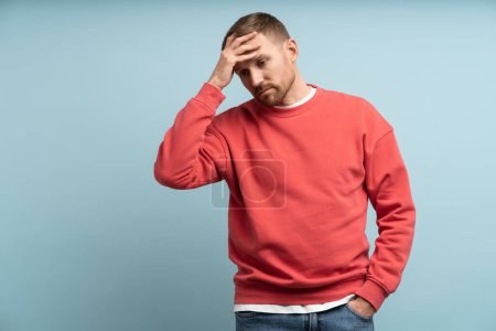 Photo for Worried man feeling heartbroken and stress put hand to forehead. Middle aged male isolated on studio blue background with expression of anxiety, detachment, shock, alienation, disappointment on face. - Royalty Free Image