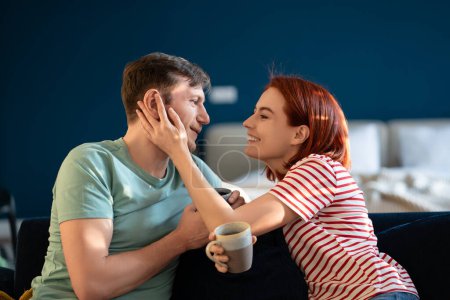 Photo for Romantic couple in love drinking coffee, tea, caress and smile happily gently. Woman and man look into each other eyes. Tenderness, love, intimacy of married couple, husband and wife. Lovers spouses - Royalty Free Image