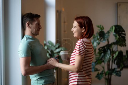 Photo for Happy middle aged couple hold hands looks at each other celebrating anniversary. Relaxed family makes plans for future in morning with tea cup. Happy relationships, trust in marriage, sincere feelings - Royalty Free Image