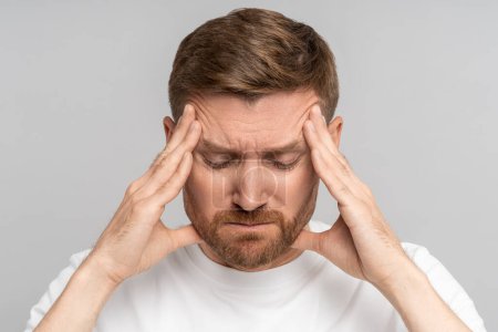 Photo for Irritated exhausted man with eyes closed presses fingers to temples from headache, failure, fatigue, difficult choose, isolated background. Overwhelmed male with professional burnout tries concentrate - Royalty Free Image