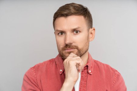 Photo for Pensive puzzled thoughtful man looking at camera touching chin isolated background. Embarrassed guy feeling confusion solves problems, struggling with choice. Haughty caucasian male pondering idea. - Royalty Free Image