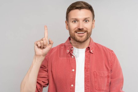 Photo for Happy enthusiastic unshaven man pointing index finger up on free studio space looking at camera. Advertising, recommendation banner for advertisement, marketing, sales, good offer, discount concept. - Royalty Free Image