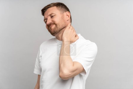 Foto de Hombre insalubre que sufre dolor de cuello después del ejercicio deportivo. Tipo frotando los músculos para aliviar el dolor o espasmo nervioso. Dolor de espalda y hernia, sedentarismo. Problemas de salud después de 40. - Imagen libre de derechos