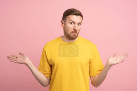 Puzzled stunned confused man gesturing hands sign do not know spreading arms by sides, isolated background. Doubtful expression on face of thinking male trying to make decision, uncertain, unsure.-stock-photo