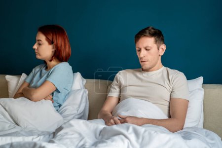 Wife husband having hard conversation sitting in bed at home trying to save relationship. Serious spouses man woman talking. Marital discord, difficult relations, adultery, betrayal, disappointment.