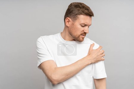 Photo for Man touching hand shoulder feeling pain isolated on gray background after injury, trauma. Neuralgia, pinched nerve in arm, broken fracture bruised arm. Health problems, bad symptom, painful concept. - Royalty Free Image