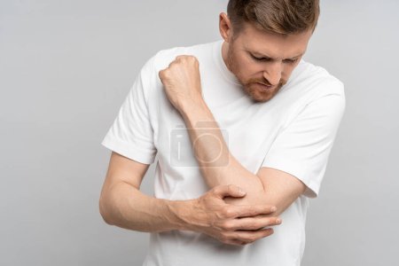 Photo for Man touching hand elbow feeling pain isolated on gray background after injury. Neuralgia, pinched nerve in arm after injury, broken fracture bruised hand. Health problems, bad symptom, hurt concept. - Royalty Free Image