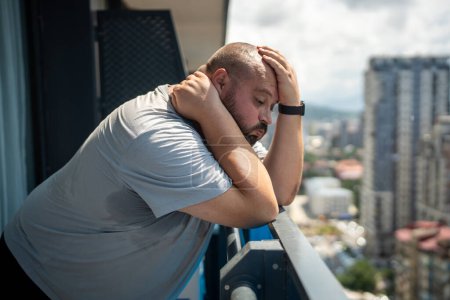 Photo for Man puffs suffers from abnormal heat. Fat, bald, bearded guy tired of disgusting, uncomfortable summer weather on balcony, breathing heavily, dying of severe sweating, high fever, humidity - Royalty Free Image