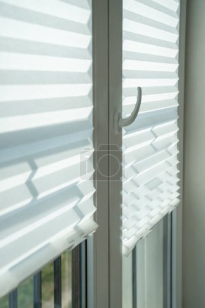 Photo for Fabric blinds on windows. Curtains jalousie louver letting light into flat and blocking flow of heat into room, keeping apartment cool, chilly. Ideal perfect sunblinds for hot and sweltering summers - Royalty Free Image