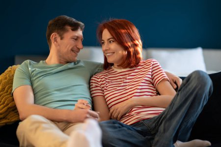 Photo for Loving married couple tender looking at each other holding hands share sincere feelings on home couch. Harmonic relationships, joy gentle candid moment. Happy man and woman hug rest in living room. - Royalty Free Image