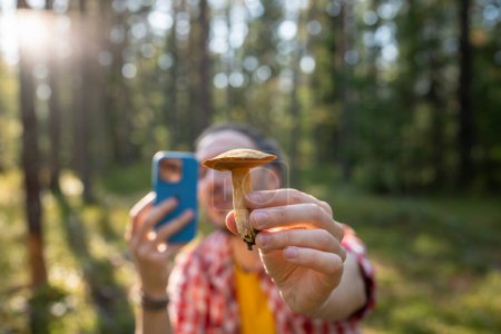 Photo for Man blogger taking photo edible mushroom on phone in forest enjoying autumn nature. Guy mushrooms picker collects fresh mushroom in woodland. Mushrooming recreation leisure outdoor activity concept. - Royalty Free Image