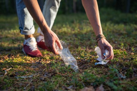 Téléchargez les photos : Homme ramassant des déchets de papier bouteille en plastique dans la forêt d'automne, protection de l'environnement. Poubelles, déchets, ordures, ordures dans les bois à l'extérieur sur la nature. Catastrophe écologique mondiale. - en image libre de droit