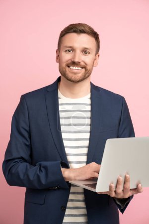Photo for Businessman with laptop isolated on pink. Successful man, employee manager IT specialist trader middle-aged guy smiling widely, happily, contentedly, gladly holding portable computer in hands. - Royalty Free Image