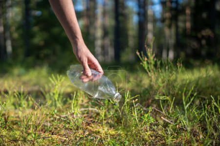 Foto de Hombre eco activista caminando por el bosque encuentra basura dejada atrás, recoge botella de plástico para preservar el medio ambiente, limpieza, cuida de la naturaleza. Salvar planeta. Turismo y conservación de ecosistemas. - Imagen libre de derechos