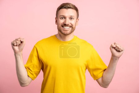 Photo for Widely smiling glad excited man clenching fists of great happiness, having goal achievement, success, good news, happy event, become father. Overjoyed man looking at camera isolated on pink background - Royalty Free Image