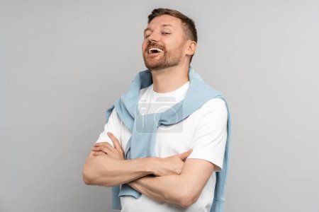 Photo for Laughing satisfied arrogant humorist with hands folded on chest standing in close pose isolated on gray background looking down. Happy positive funny guy in good mood. Sincere human emotions concept. - Royalty Free Image