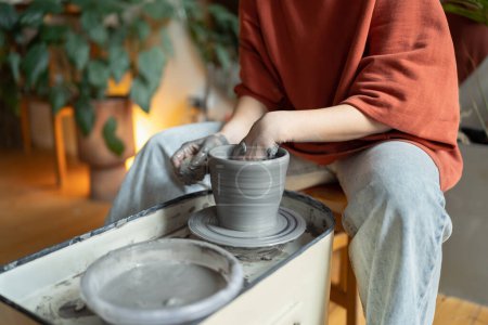 Photo for Hands of craftswoman ceramist working sitting in cozy workshop using potter wheel for make clay tableware. Process of creating handmade chinaware in art studio for creative entrepreneurs and artisans - Royalty Free Image