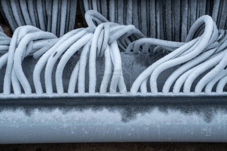 Téléchargez les photos : Tuyaux réfrigérés flexibles torsadés recouverts de givre. Système d'ingénierie pour le refroidissement de patinoire rempli d'eau gelée. Préparation et installation d'une patinoire extérieure pour l'hiver - en image libre de droit