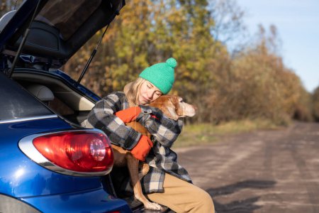 Photo for Middle aged woman in road trip with dog hugging pet sitting in car trunk during break on nature. Affectionate dog lover tenderly hugs animal with closed eyes feels harmony. Travel tourism road trip. - Royalty Free Image