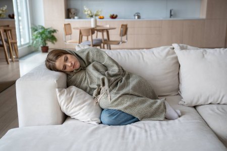 Photo for Sad tired girl lying alone feels depression apathy indifference to everything melancholy attack has mental problems. Unhappy young woman warming wrapped with plaid from central heating problem at home - Royalty Free Image
