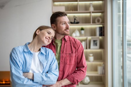 Photo for Amiable cheerful happy woman and tender caring attentive man standing in silence in own flat, looking at window, dreaming, thinking on relations, love, family, togetherness, future plans, children - Royalty Free Image