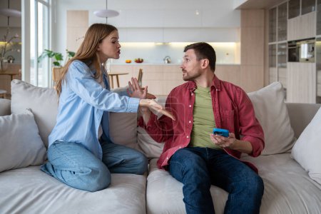 Photo for Spouses having conflict, quarrel, scandal, crisis, shouting, lashing out at family partner. Angry woman shouting at man, pointing at mobile phone. Defensive husband bringing arguments, explanations - Royalty Free Image