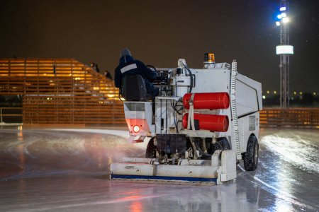 Photo for Ice preparation at rink. Ice recovery and maintenance machine on skating rink in the evening. Winter sport, leisure, holiday concept - Royalty Free Image