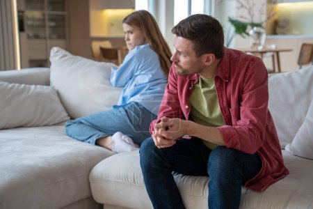 Photo for Couple man woman ignoring each other sitting on couch in silence at home turning away. Frustrated spouses offend after family quarrel. Domestic violence abuse neurotic relationships, misunderstanding. - Royalty Free Image