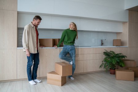 Photo for Happy smiling wife looking at spacious new apartment. Cheerful husband delighted with bying own flat, house. Cardbord boxes with belongnings, goods standing on floor. Relocation day to new property - Royalty Free Image