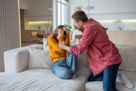 Photo for Abuser tyrant husband fighting wife screaming sitting on couch at home. Jealous man suspects woman of cheating. Toxic relationship, abuse, domestic physical emotional violence, manipulation scandal. - Royalty Free Image