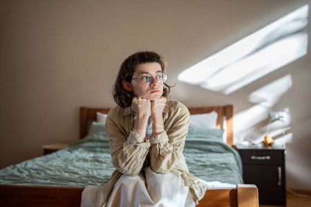 Photo for Depressed lonely woman sitting on cozy bed sadly look at window feeling anxiety. Alone girl suffering from emotional pain having life troubles, problems. Mental disorder anhedonia, stress discomfort - Royalty Free Image