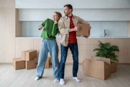 Photo for Joyful happy glad woman dancing in spacious apartment, celebrating flat putchase, independent living, relocation to own new apartment. Cheerful man holding packed cardboard box with belongings - Royalty Free Image