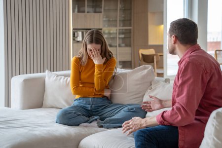 Photo for Family conflict misunderstanding between spouses. Man screaming shouting gesturing hands. Toxic relationship, manipulation. Woman cry discussing with cruel man in abusive relations sits on couch. - Royalty Free Image